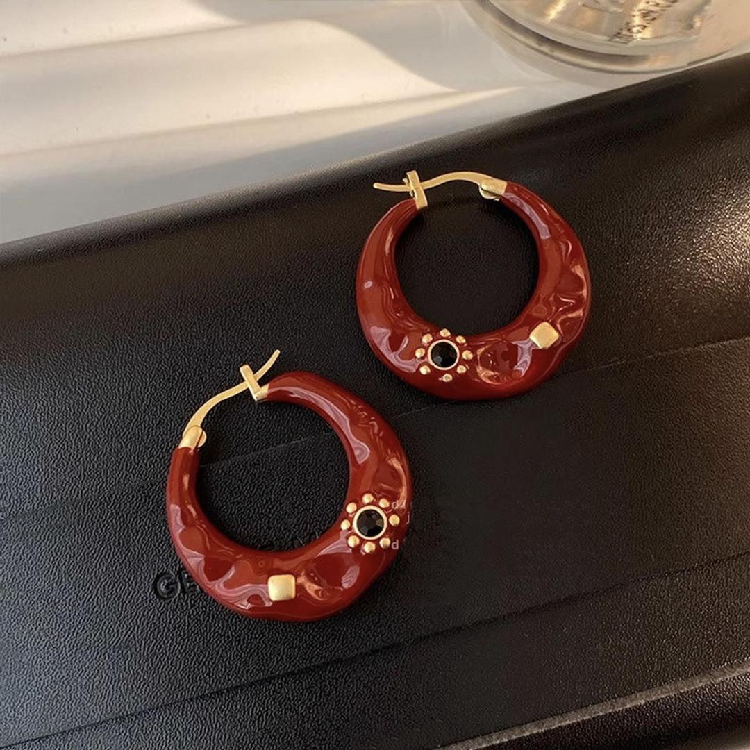  Elegant luxury brown enamel hoop earrings with gold-tone details and black gemstone accents, displayed on a black textured surface.